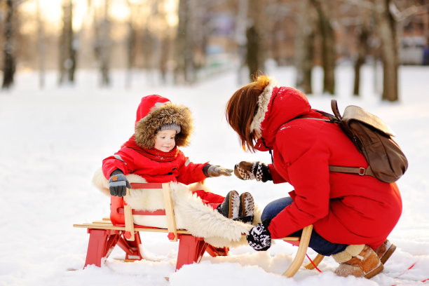 漂亮的蹒跚学步的男孩和他的母亲在冬天玩得开心图片下载