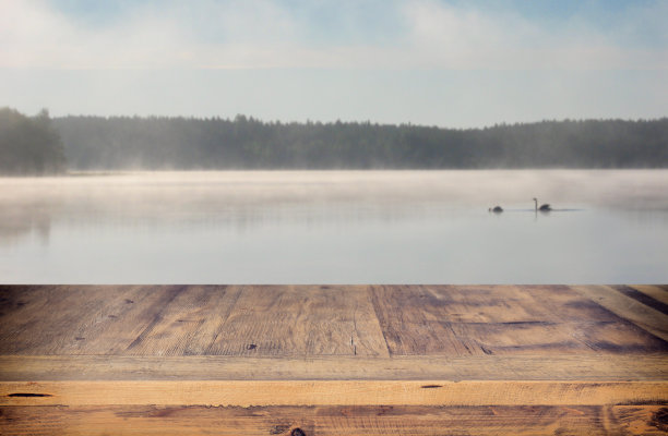 复古的木板桌子前的抽象照片，雾蒙蒙的湖在早晨/晚上。图片下载