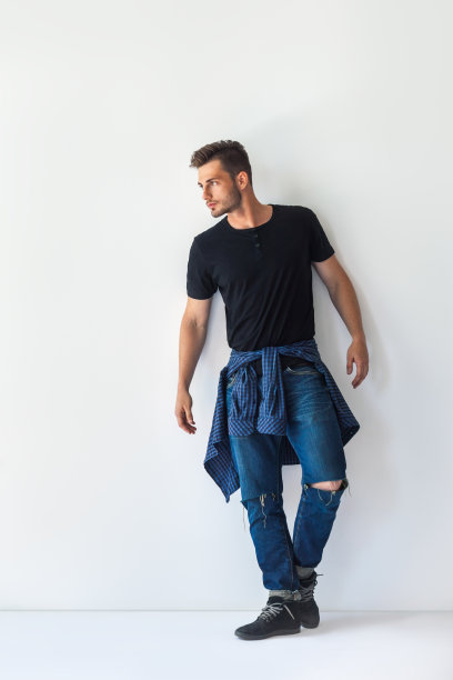 英俊的时尚男子的全长肖像倚在白色的墙壁图片下载