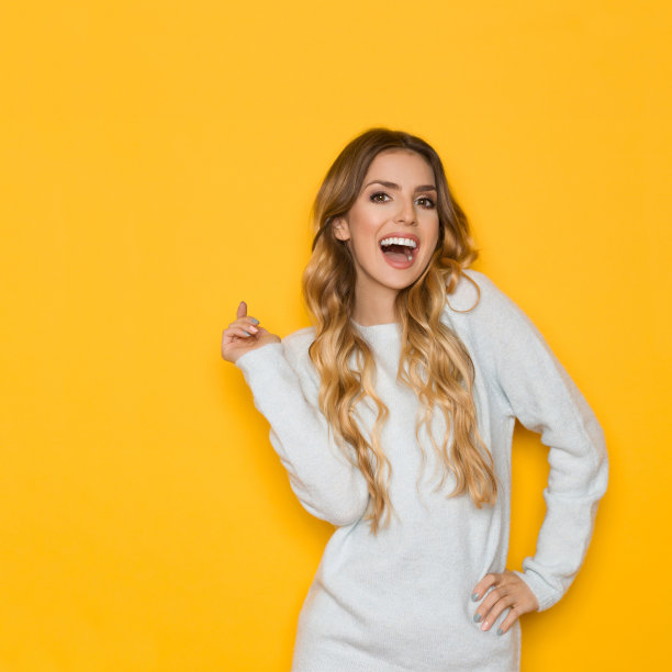 穿着柔和毛衣的笑着的年轻金发女人图片下载