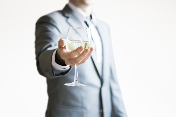 一个穿着浅灰色西装的商人拿着一杯白葡萄酒庆祝成功的照片图片下载