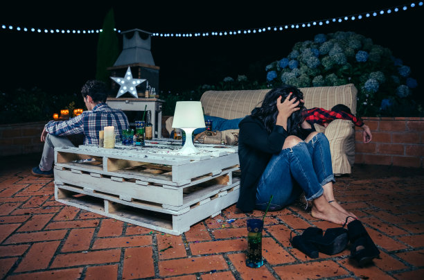 派对结束后坐在地板上喝醉的年轻女人图片下载