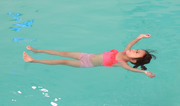 小女孩在游泳池的水面上漂浮着。图片下载