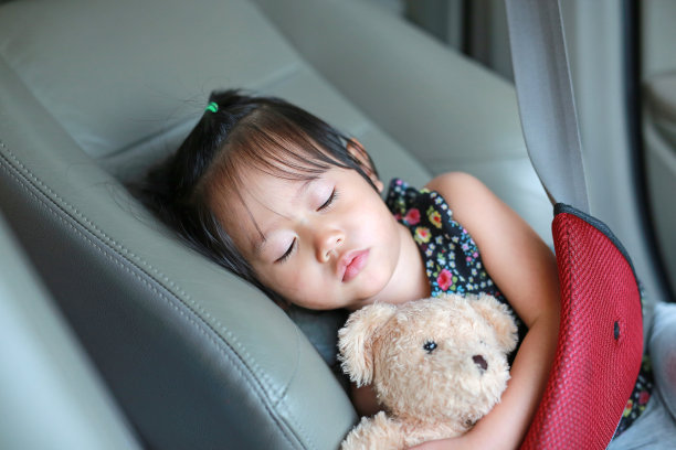 在汽车安全带里睡觉的孩子。素材图片