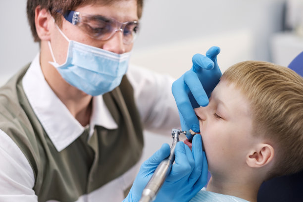 一位男牙医正在检查这个开朗的男孩的牙齿图片下载