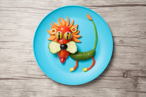 用蔬菜做成的狮子放在蓝色的盘子和桌子上图片下载