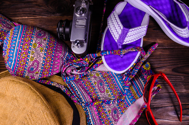 游泳衣，帽子，人字拖，太阳镜和旧相机放在木桌上。前视图。暑假的概念图片下载