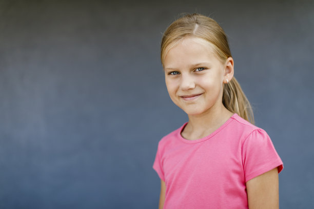 在灰色背景上摆姿势的小女孩的肖像图片下载