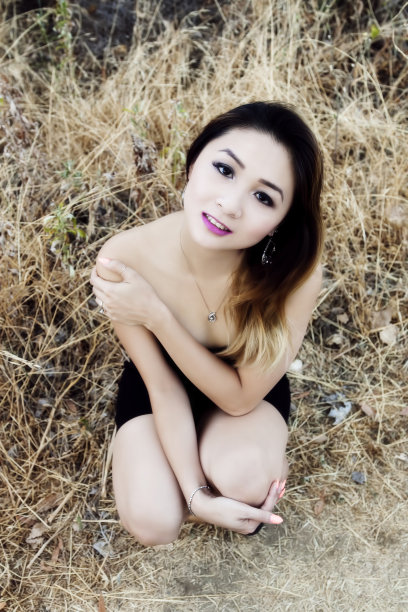 迷人的亚裔美国女人蹲在户外黑衣图片下载