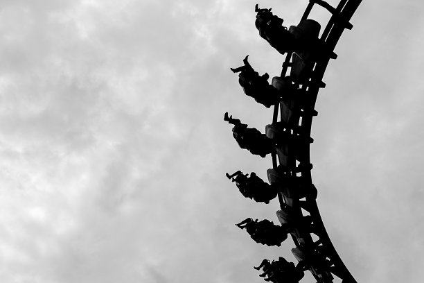 黑人和白人乘坐云霄飞车，双腿来回摆动，如同地心引力。素材图片