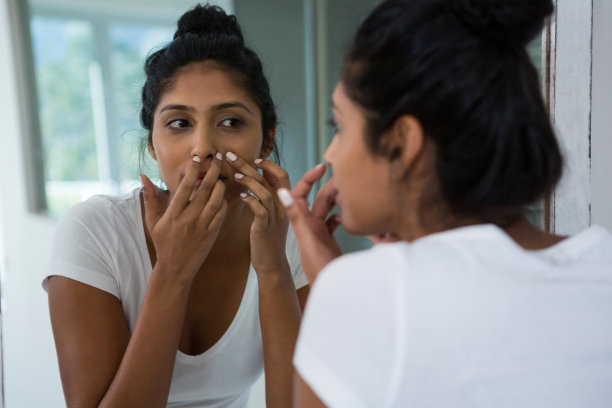 女人捏着镜子里的青春痘素材图片