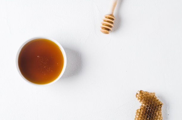 白色混凝土背景下，白色杯子里的新鲜蜂蜜图片下载