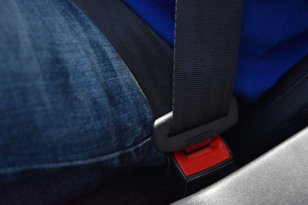 穿着牛仔裤和蓝色衬衫的男人的特写安全带锁，驾驶安全。图片下载