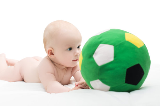 小男孩或小女孩趴在地上玩着足球，孤立地躺在白色的地上图片下载