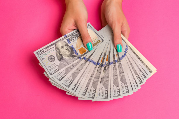 一个女人手里拿着钱。粉红色的背景。俯视图拷贝空间图片下载