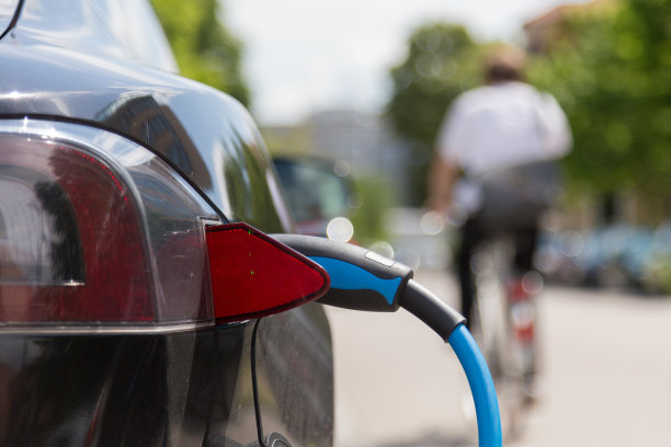 电源插入正在充电的电动汽车。图片下载