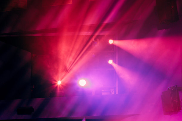 演出期间剧院舞台上的照明设备。聚光灯发出的光线穿过烟雾。红色和紫色光束图片下载