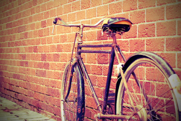 一辆旧自行车停在一堵砖墙旁边。背景图像的概念。后面的观点。复古的基调。有选择性的重点。图片下载