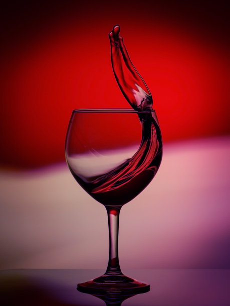 红玫瑰酒诱人的抽象泼洒在渐变背景的白色、粉色、紫色和红色的反光表面上图片下载