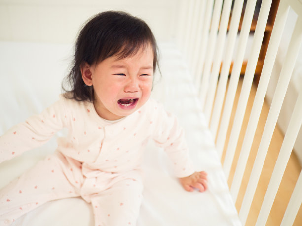 女婴在婴儿床里哭泣素材图片