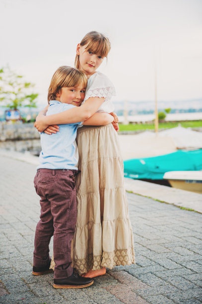 户外肖像两个可爱的孩子拥抱对方，小男孩和女孩花时间在一起，垂直形象图片下载