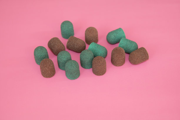 喷砂帽。棕色和绿色研磨帽在粉红色的背景上图片下载