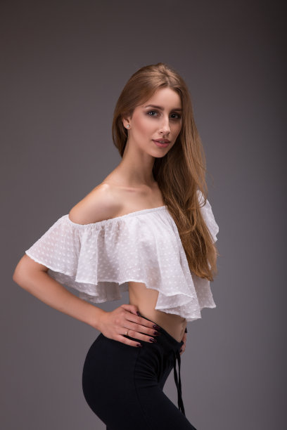 迷人的女人在白色衬衫摆姿势在灰色的背景图片下载