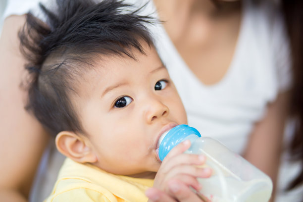 漂亮的妈妈在家里用奶瓶喂小男孩素材图片