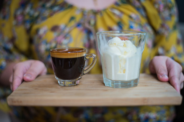 一个女人的手拿着一杯Affogato咖啡或浓缩冰淇淋在木板和模糊的背景图片下载