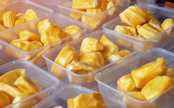 将菠萝蜜切成块放在塑料盒中，准备在当地水果市场出售素材图片