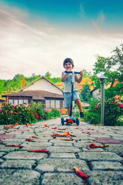 可爱的男孩在户外驾驶滑板车图片下载