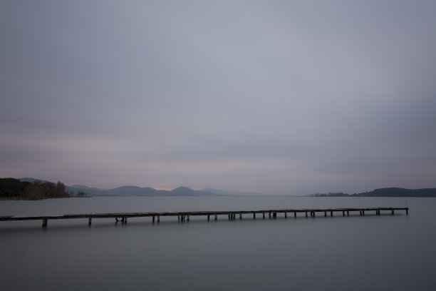 黄昏时湖面上的一个长长的码头，水面平静，云在移动图片下载