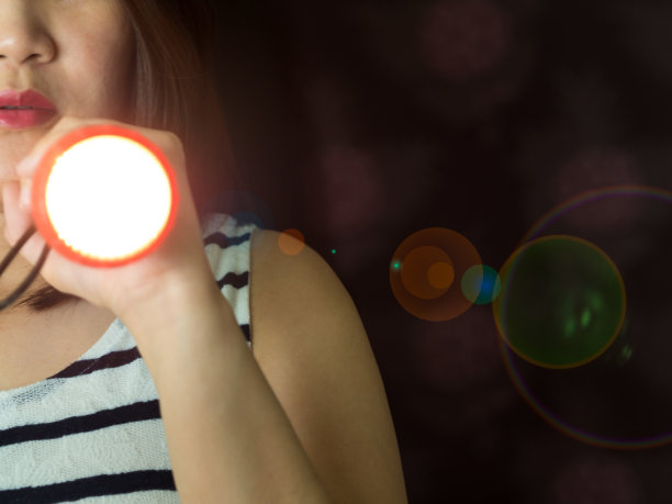 部分亚洲妇女手持手电筒在黑暗中窥视门素材图片