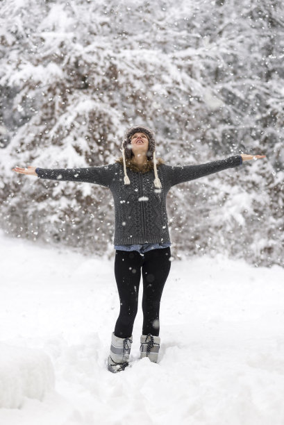 一个女人站在白雪覆盖的森林里双臂张开图片下载