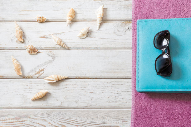 白木色背景的沙滩毛巾、太阳镜和夏日配饰。旅行的概念。从以上观点。空白模型的广告或包装。图片下载