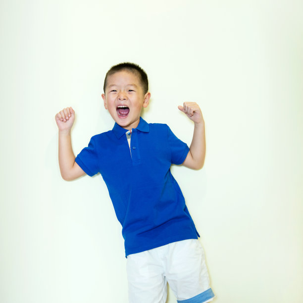 小男孩靠墙站着，露出他的肌肉素材图片