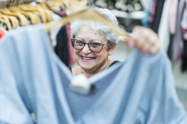 这位满头银发、活跃的65岁老妇人正在一家服装零售店购物素材图片