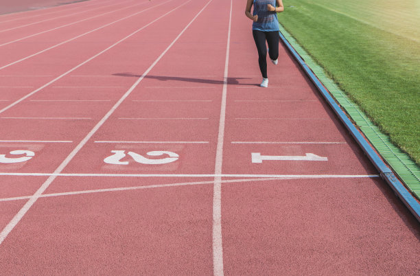 女运动员以第一名的成绩冲过终点线。在体育场的跑道上。图片下载