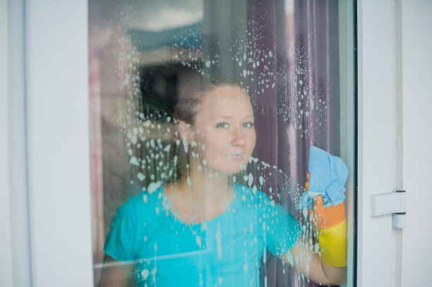 漂亮的女保洁员一边做家务一边喷雾器，洗窗户图片下载