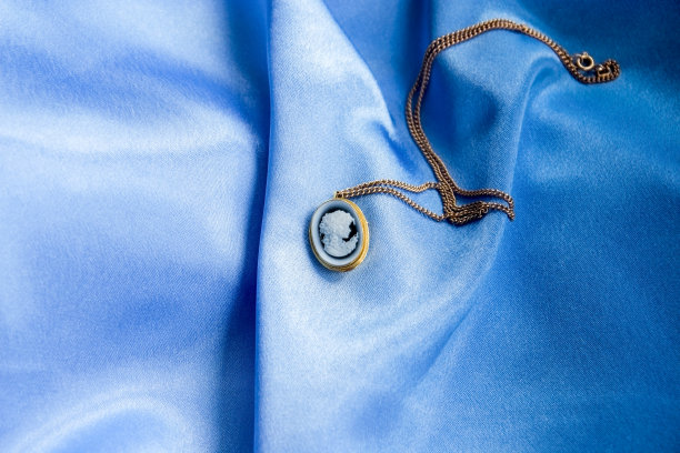 饰有浮雕的金链，在光滑的天蓝色丝绸上雕刻出女性的轮廓图片下载