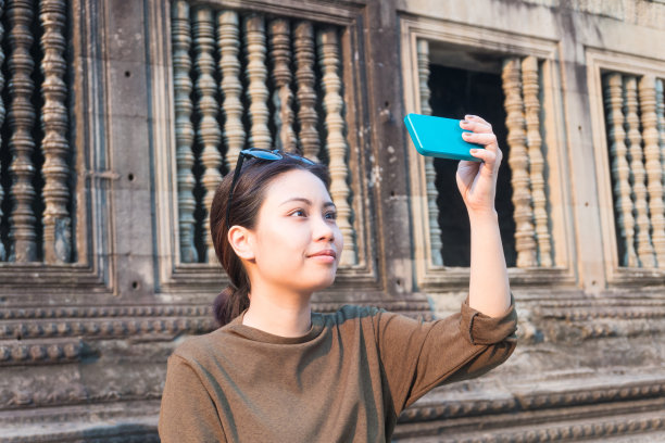 在柬埔寨吴哥窟，女游客用智能手机自拍图片下载