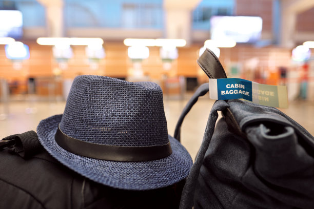 机场的长凳上放着手提行李和一顶旅客帽子图片下载
