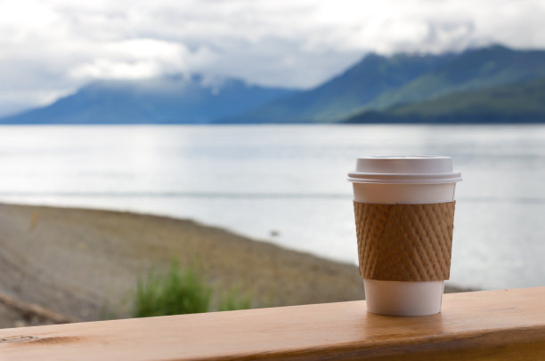 一个塑料咖啡杯放在户外的木桌上。图片下载