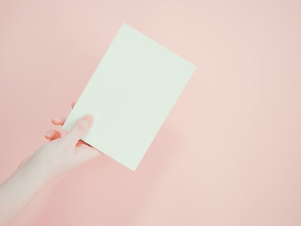 亚洲妇女拿着并呈现她的书或文件展示用一只手与粉红色的粉彩背景图片下载