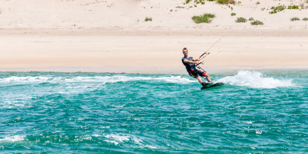 风筝滑板男子在白沙滩前转弯的照片图片下载