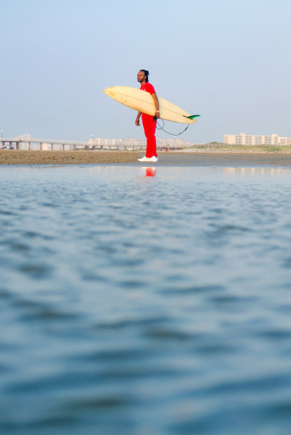 一个男人在海滩上拿着冲浪板图片下载