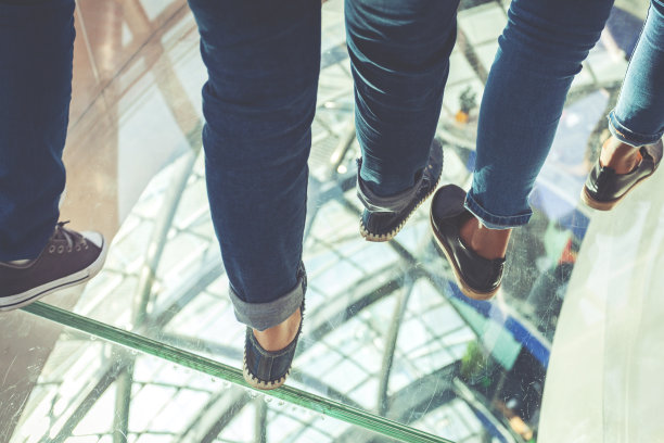 年轻人的腿在玻璃表面上行走。图片下载