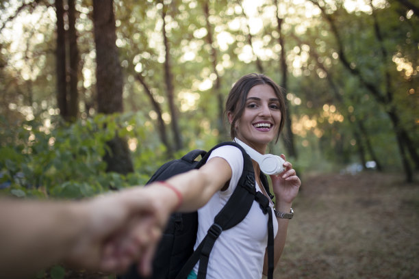 两个徒步旅行者在大自然中牵手渡过小溪图片下载