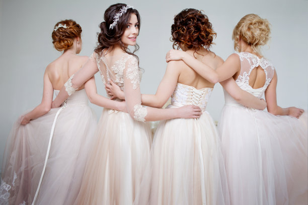 新娘在婚礼沙龙。四个美丽的女孩相互拥抱着。背部，特写蕾丝裙图片下载
