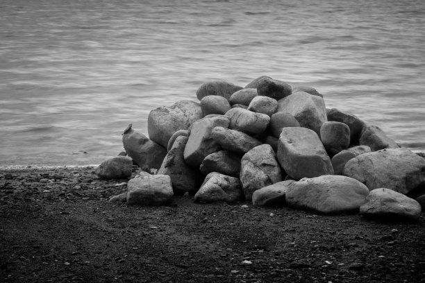 黑色和白色的岩石堆在岸上图片下载